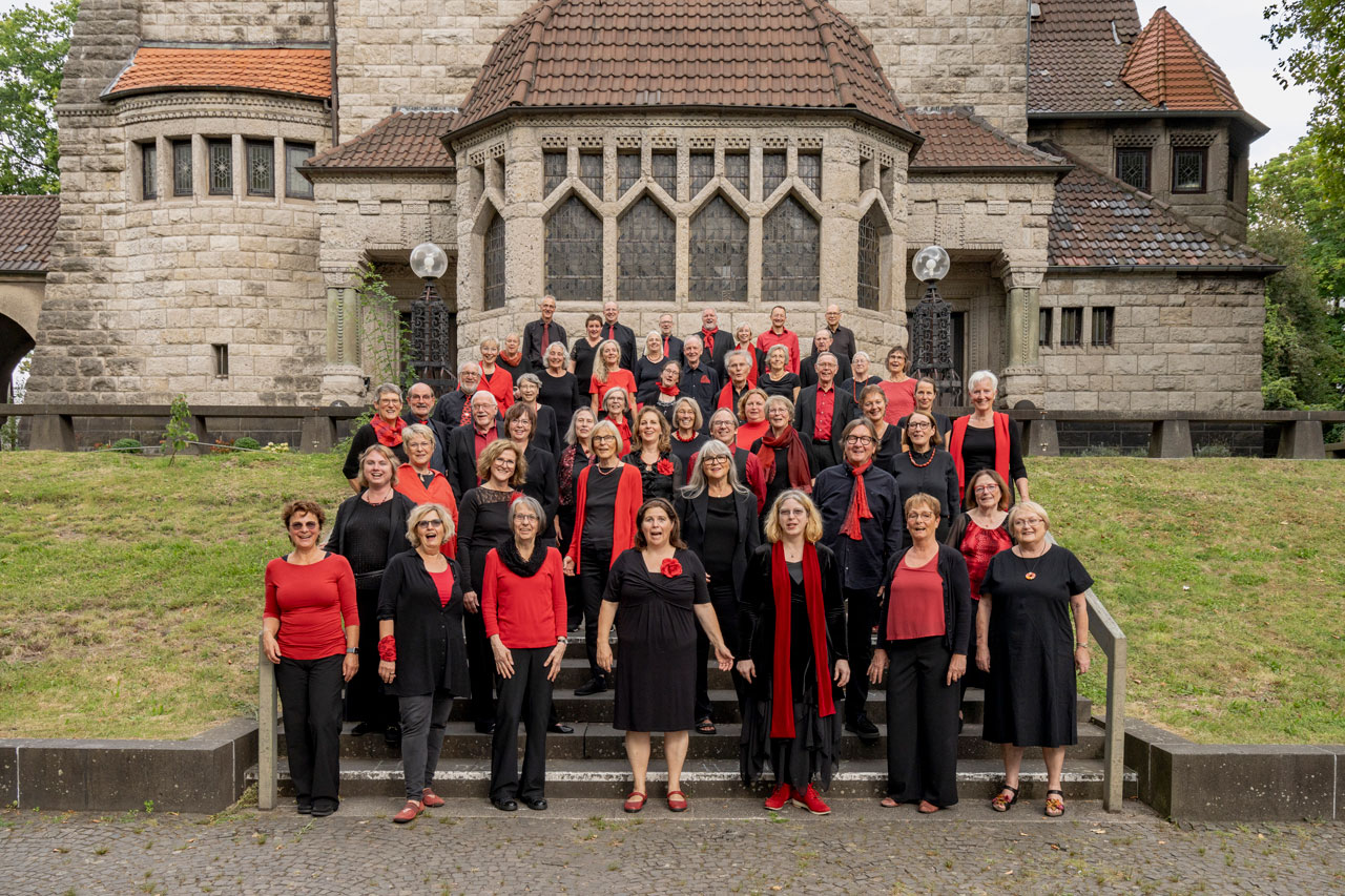 Die Sängerinnen und Sänger des profanen chores stehen vor der Lutherkirche am Stadtpark Bochum